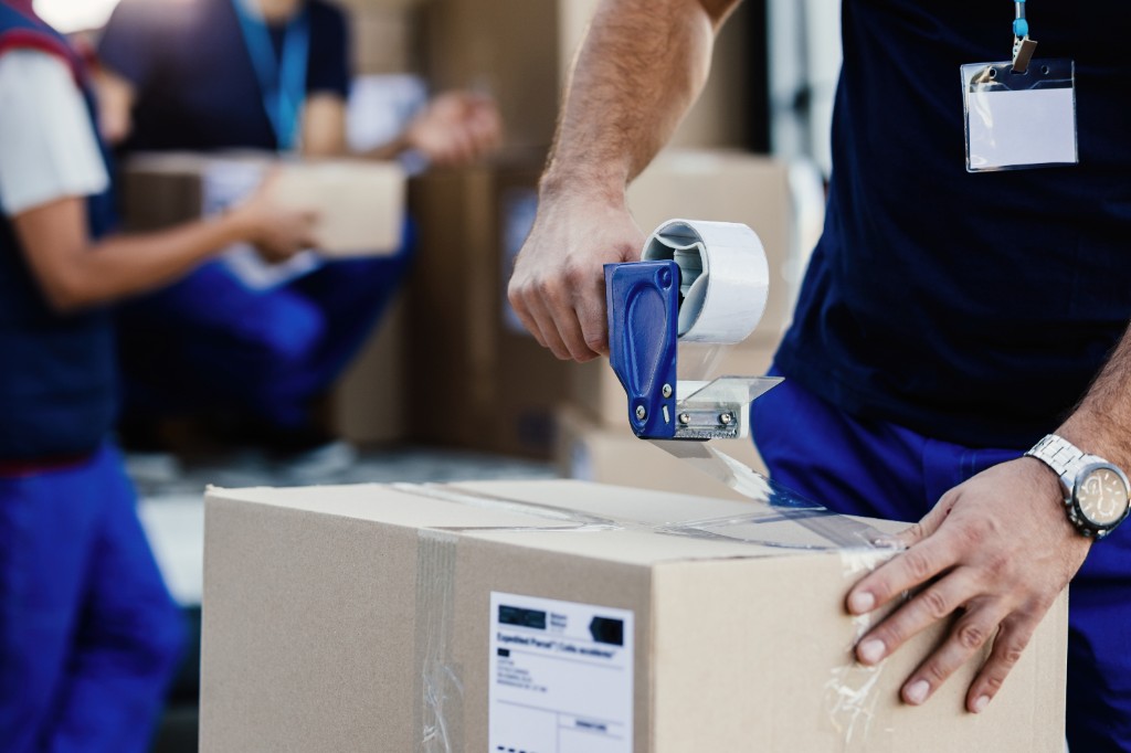 Packservice: Umzugskarton wird sicher mit Packband verschlossen